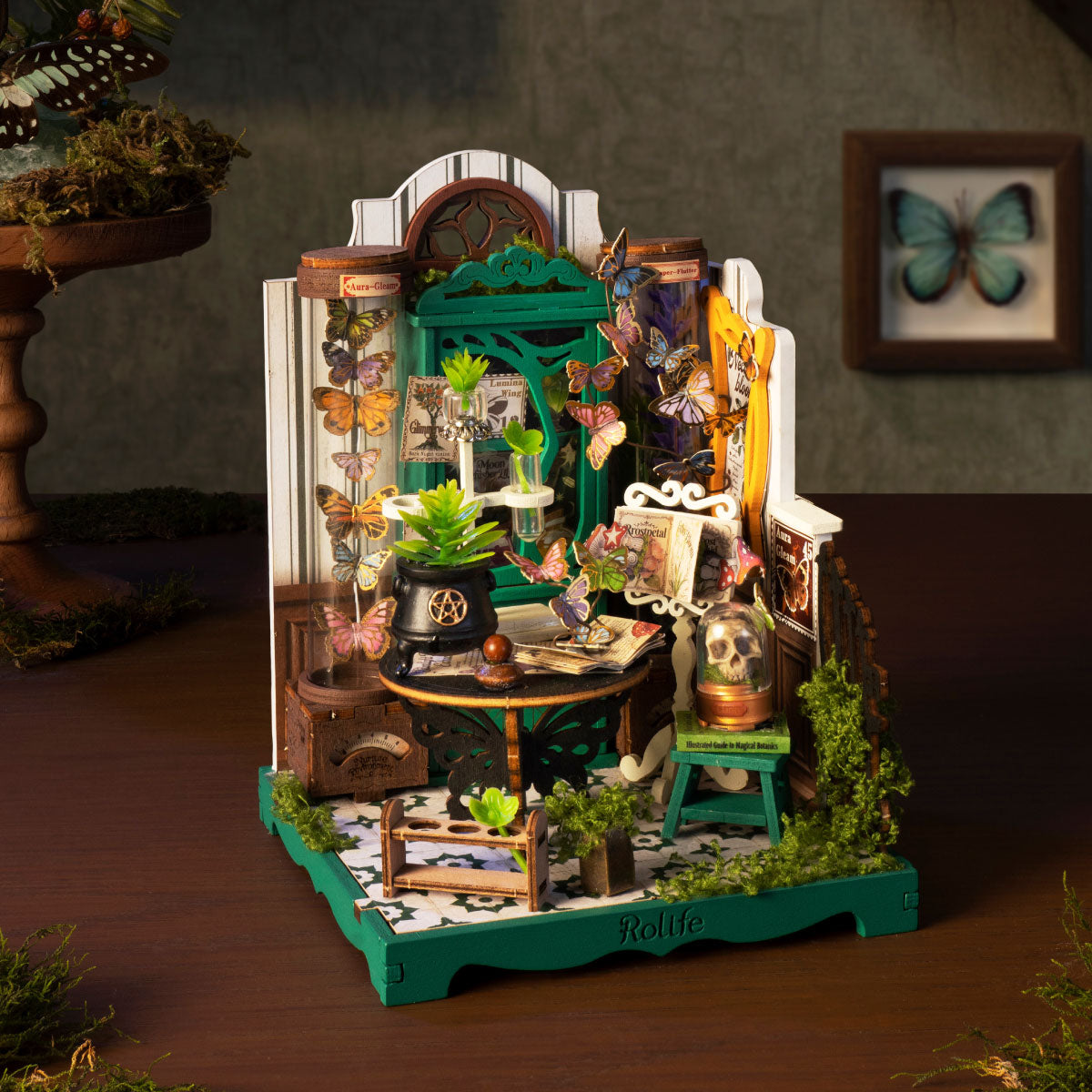 Rolife Potions Workshop DS057 displayed on a desk with butterflies, green apothecary cabinet, cauldron, skull dome and warm moody lighting