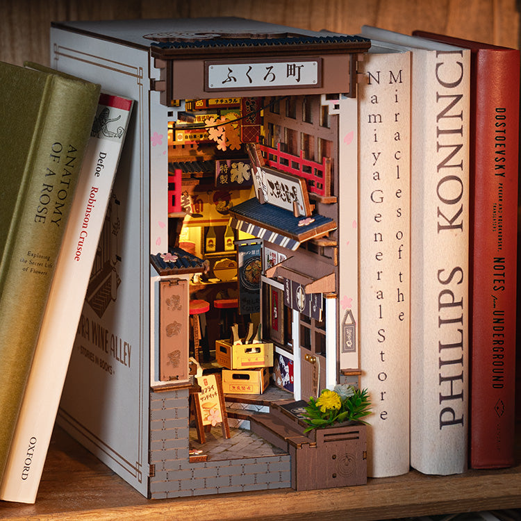 Rolife Sakura Wine Alley inside a book with books surrounding it.