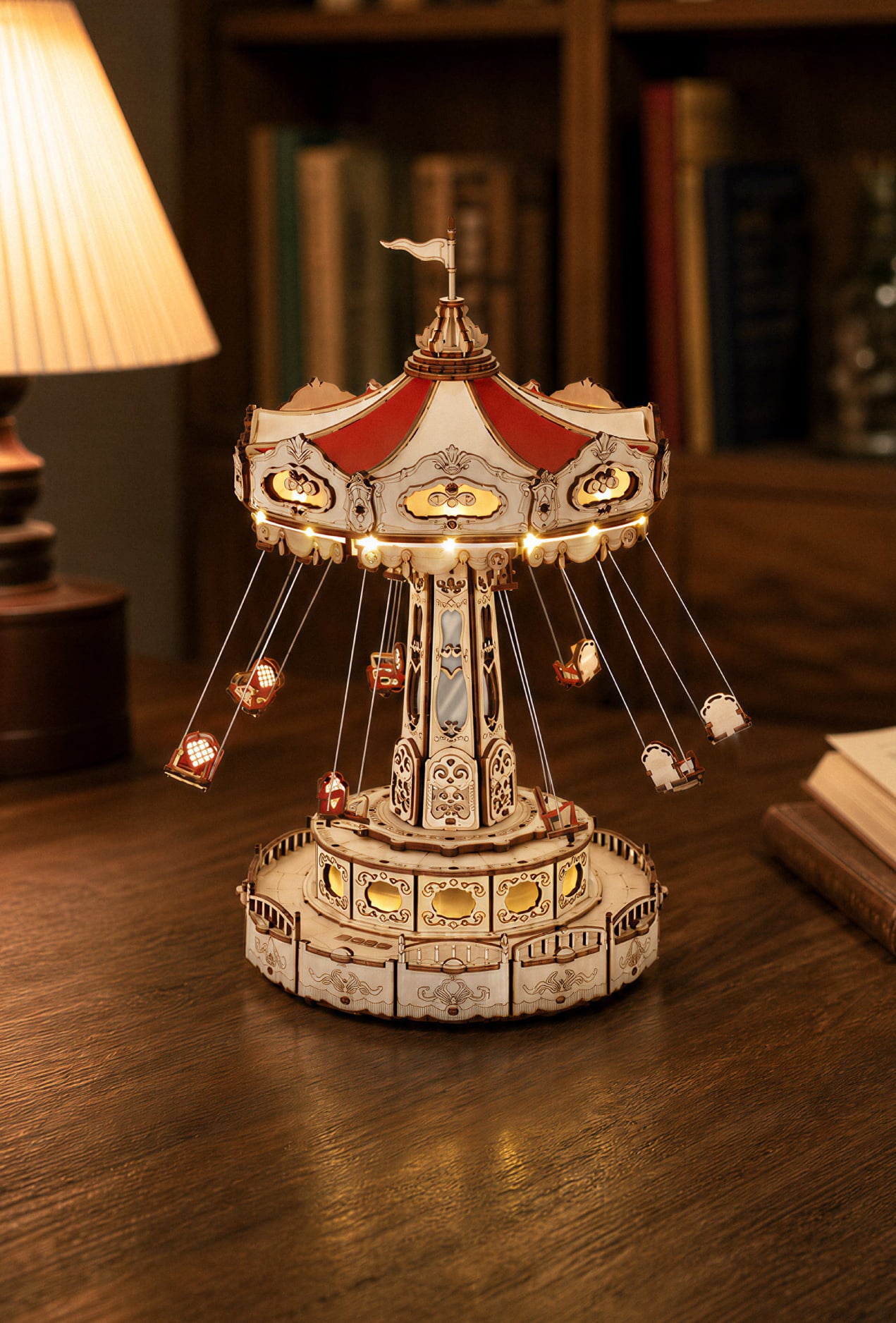 Wooden carousel music box glowing beneath a red canopy on a dark library table