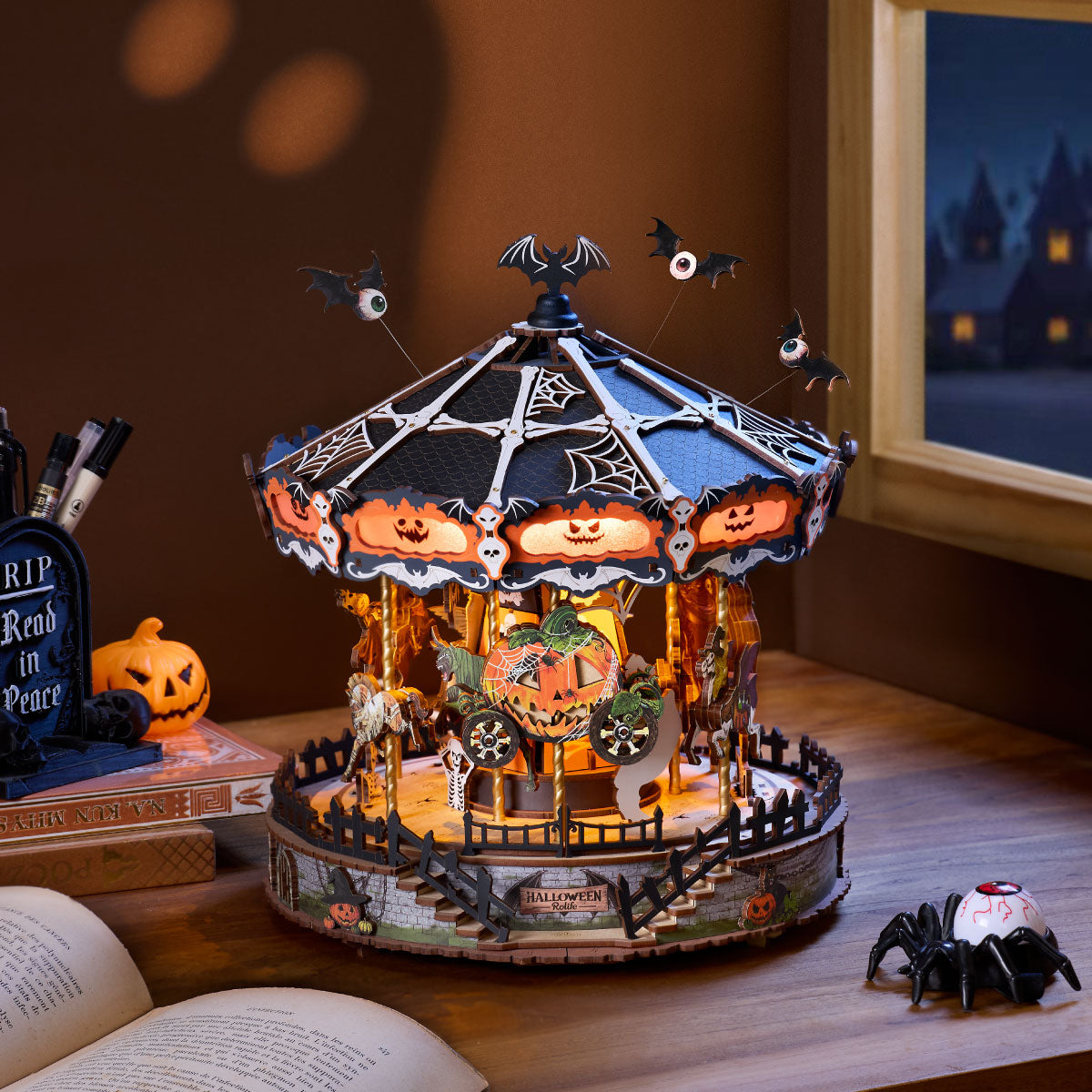 Rolife Phantom Waltz DIY Music Box AMS04 tabletop Halloween display with glowing carousel, open book, pumpkin, window, and spider decor
