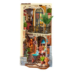 Rolife miniature art shop diorama with arched balcony, blue-framed window, potted plants, framed artwork, blue pendant lamp and small table.