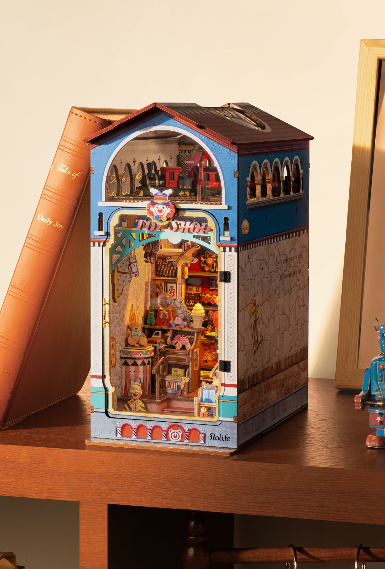 Tall Rolife book nook with blue roof, arched windows and a warmly lit street interior